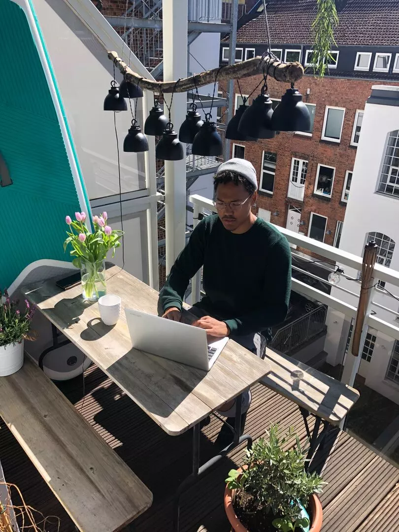 The young man with laptop is sitting on the balcony