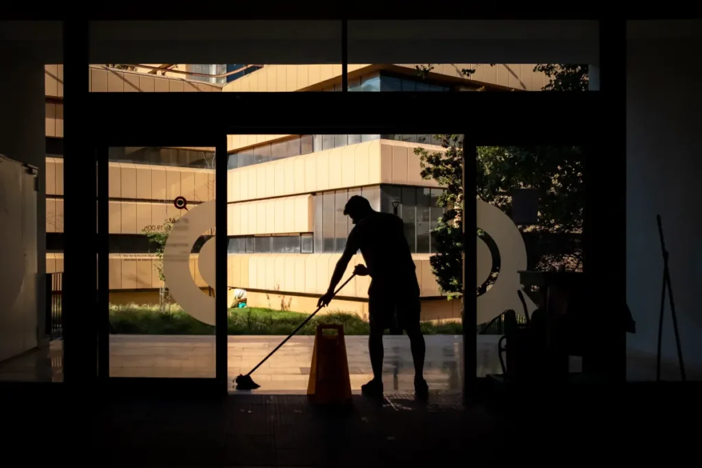 Man cleans floor at an entrance door